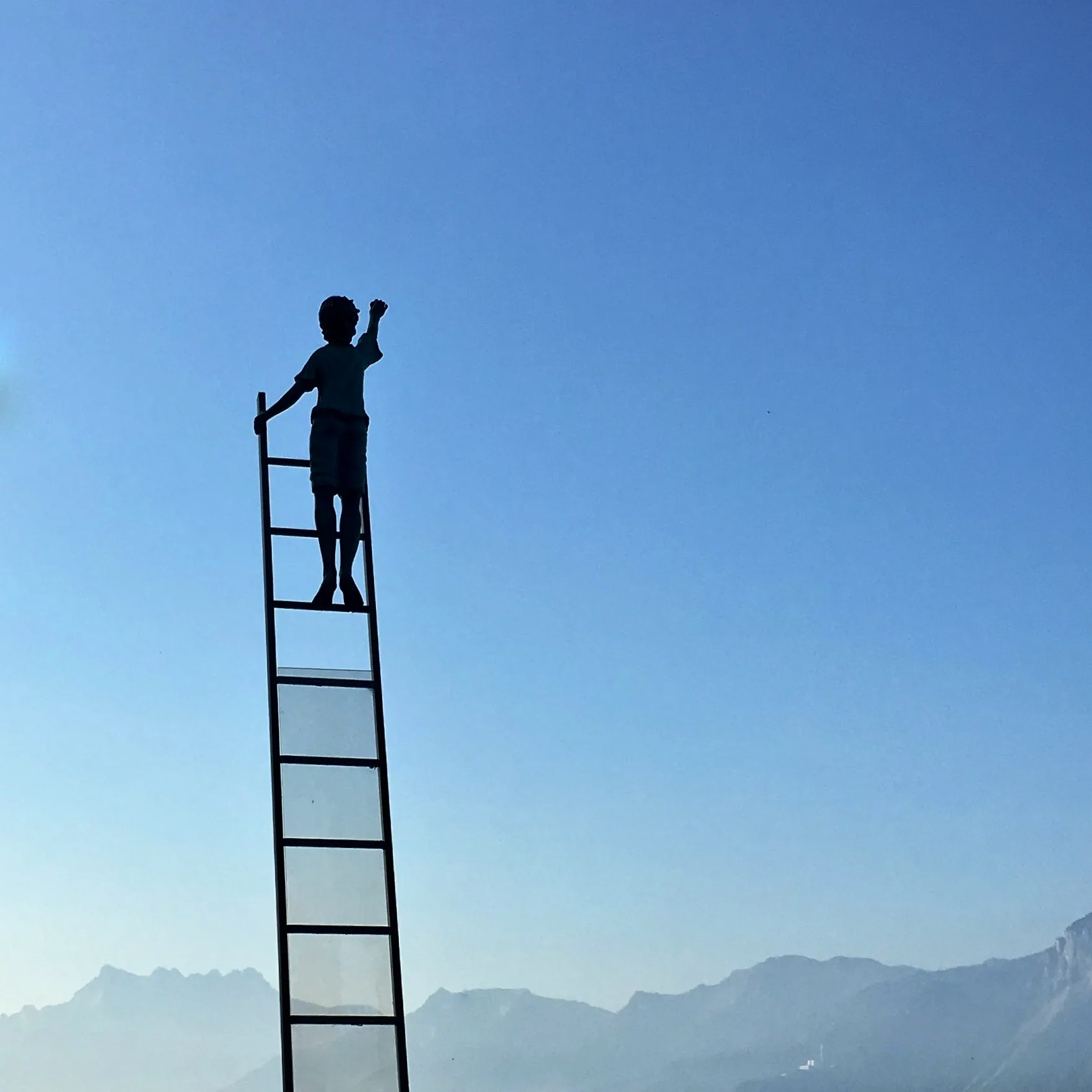 woman on a ladder reaching high in the blue sky