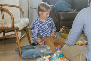 A young boy seated on the floor enjoying his Easter egg hunt results.