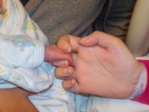 mother holding child's hand at birth